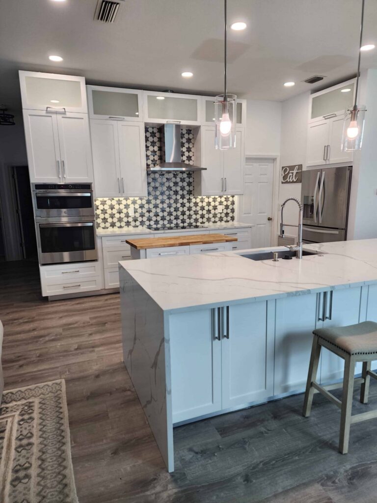 White upper cabinets with glass-front top doors around a kitchen range hood