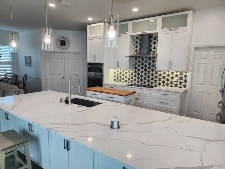White kitchen wall cabinets above a patterned backsplash and cooking area