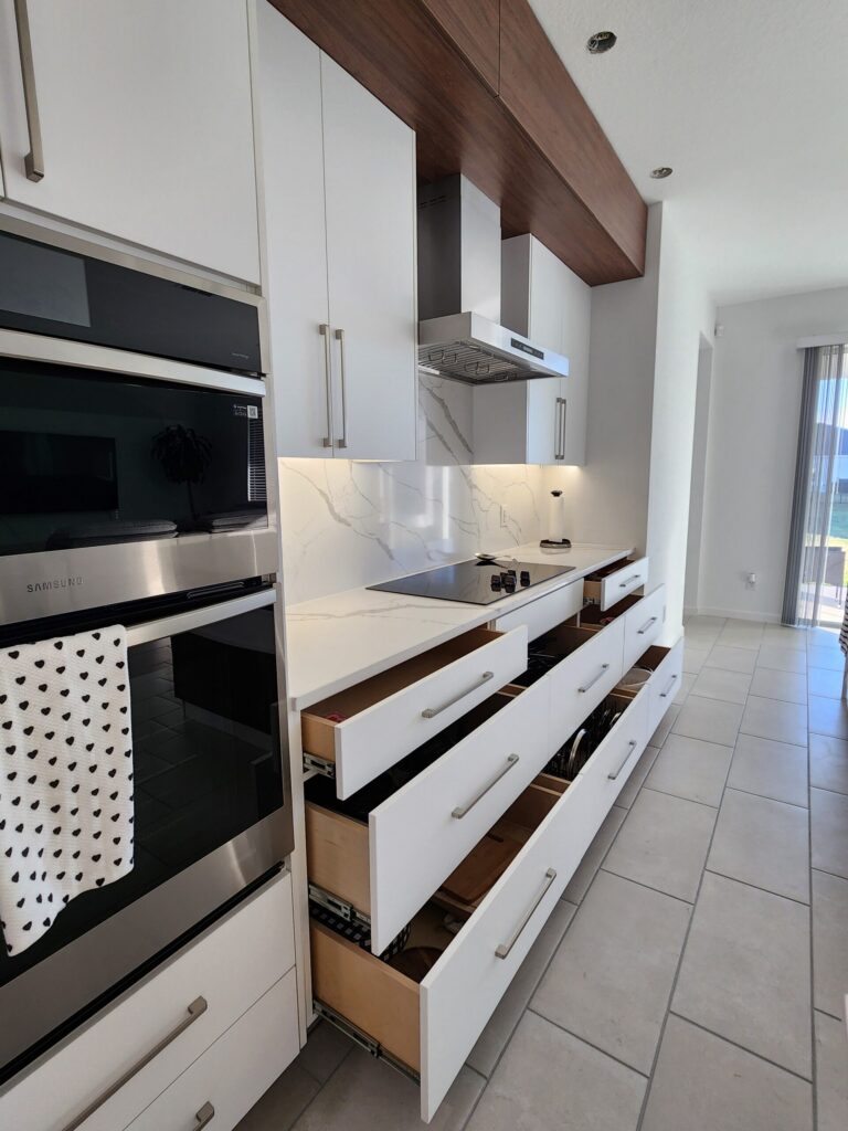White upper kitchen cabinets beside a range hood and built-in wall oven