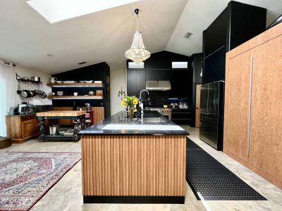 Kitchen Cabinets 16 Contemporary kitchen with wood slat island, black cabinetry, and luxury chandelier lighting.