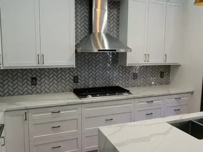Kitchen Cabinets 73 Modern white custom kitchen with shaker cabinets, stainless steel hood, and geometric backsplash.